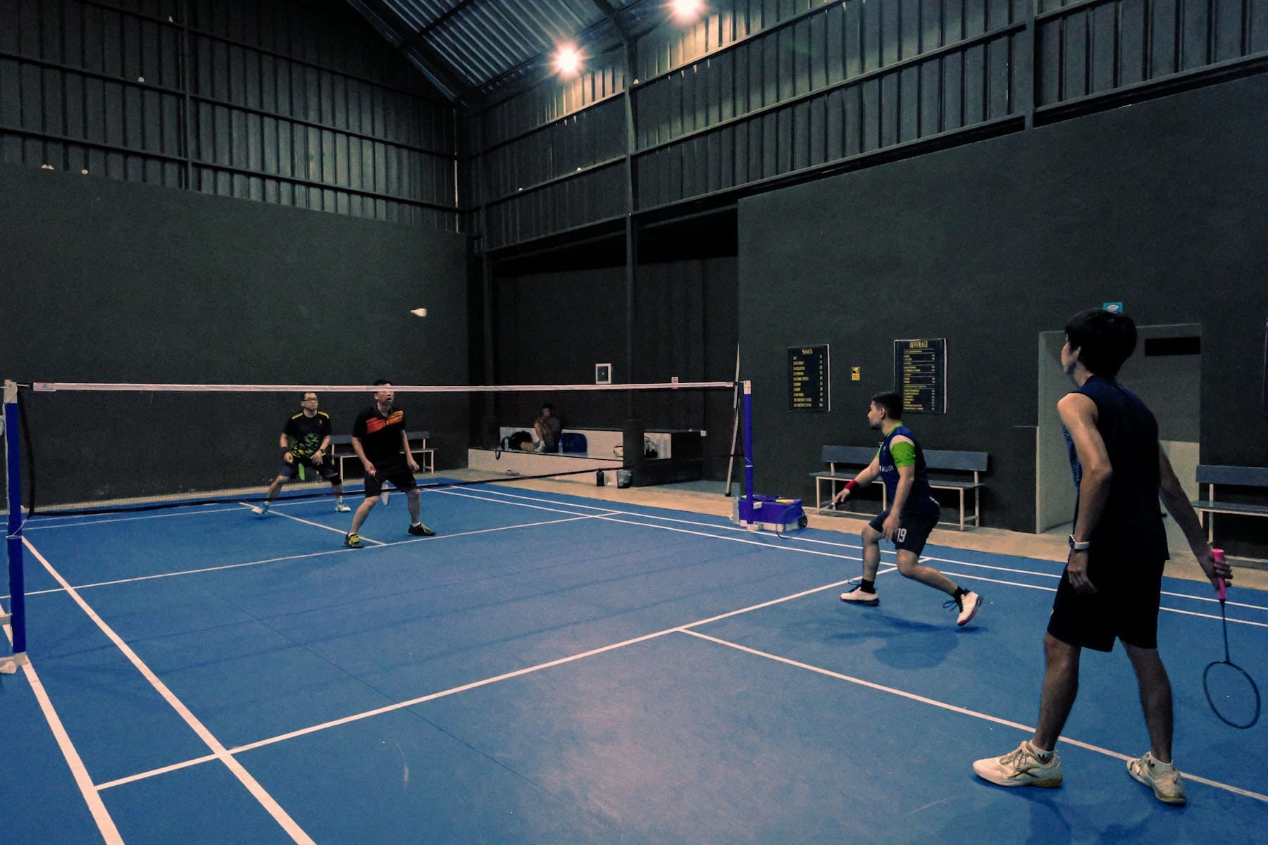 Doubles badminton on several courts in an indoor hall