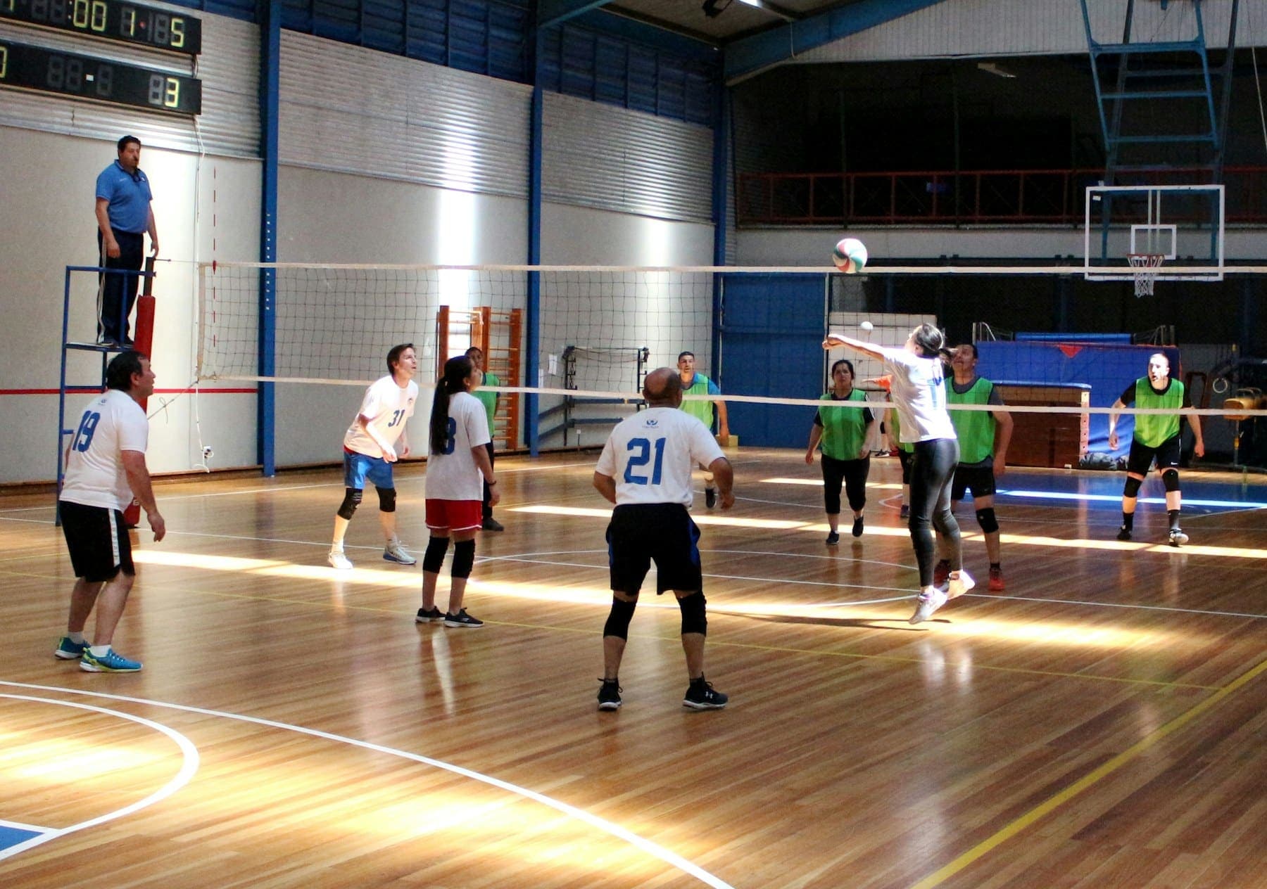 A social volleyball game on a wooden floor in an indoor sports hall